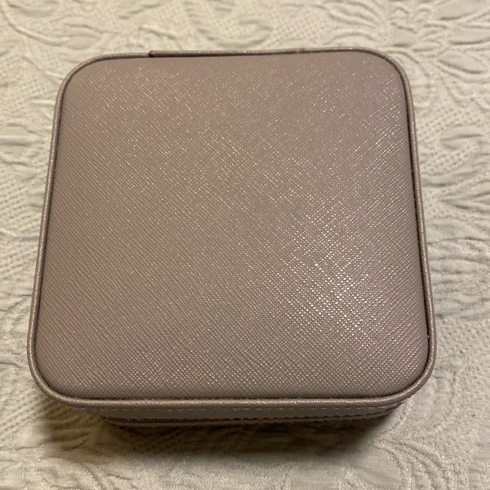 Gray leather jewelry travel box with cream interior and a mirror and zip close.